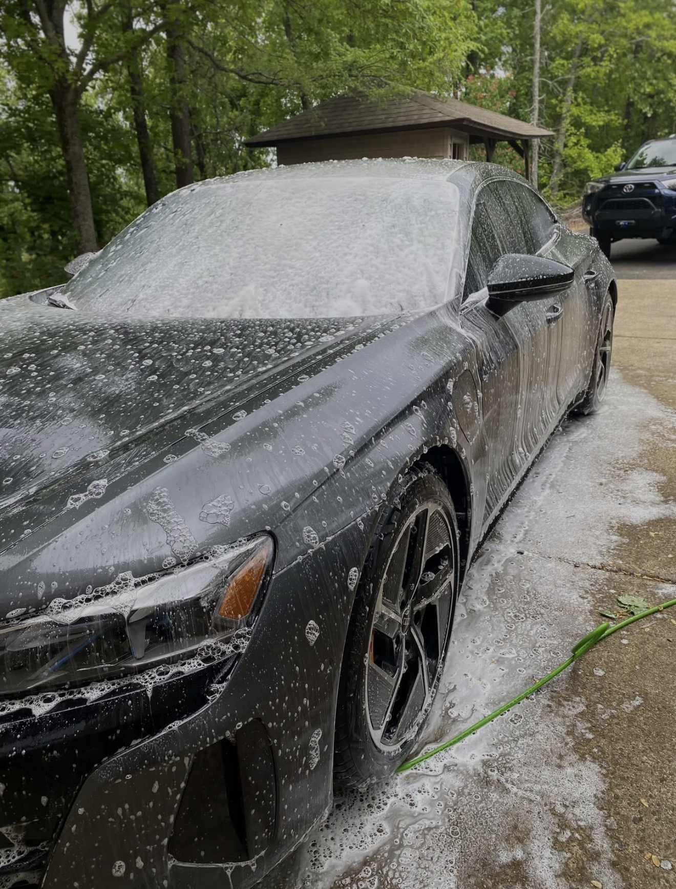 Audi e-tron GT covered in thick foam wash — front quarter view