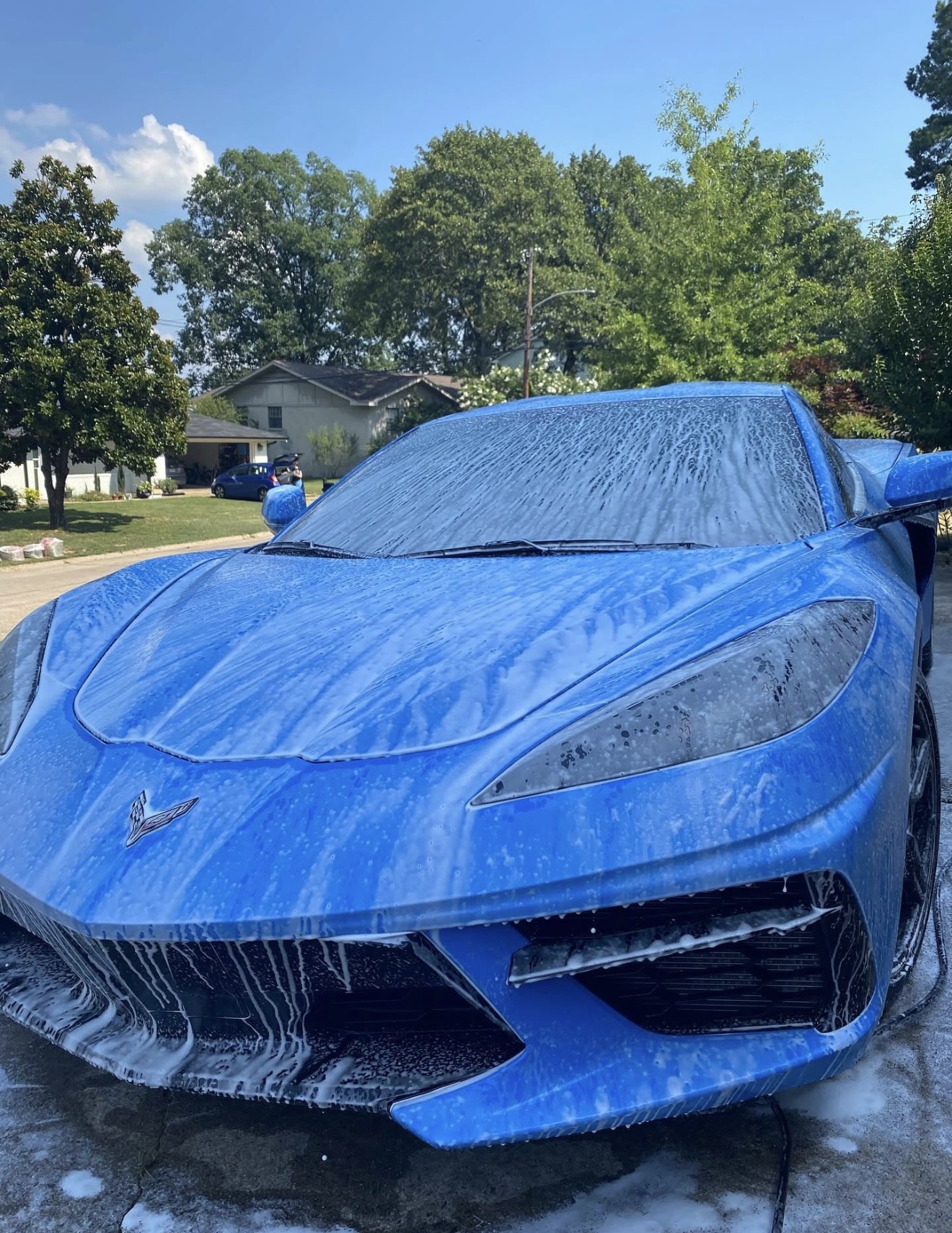 Blue C8 Corvette covered in thick foam wash on the driveway